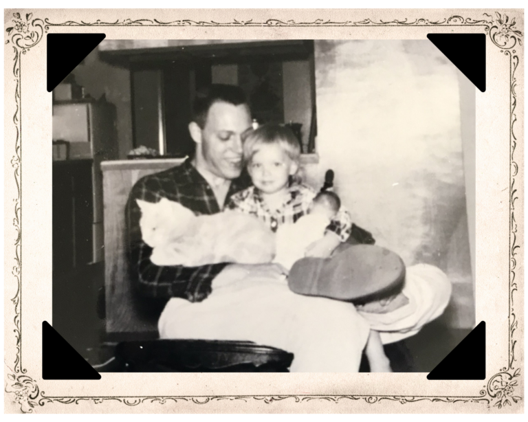 Photo of author at about age three snuggled into her dad's lap with his left arm, dad smiling at her as she smiles toward camera shyly, and cat on his lap beside her, facing away and resting the front of its body on his right arm.